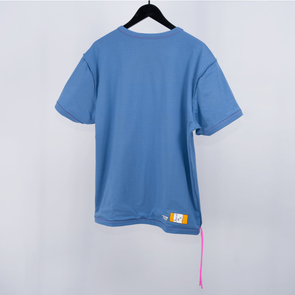 Blue t-shirt on a hanger with two pink cords hanging off the bottom corner and a small design also at the bottom against a light gray background