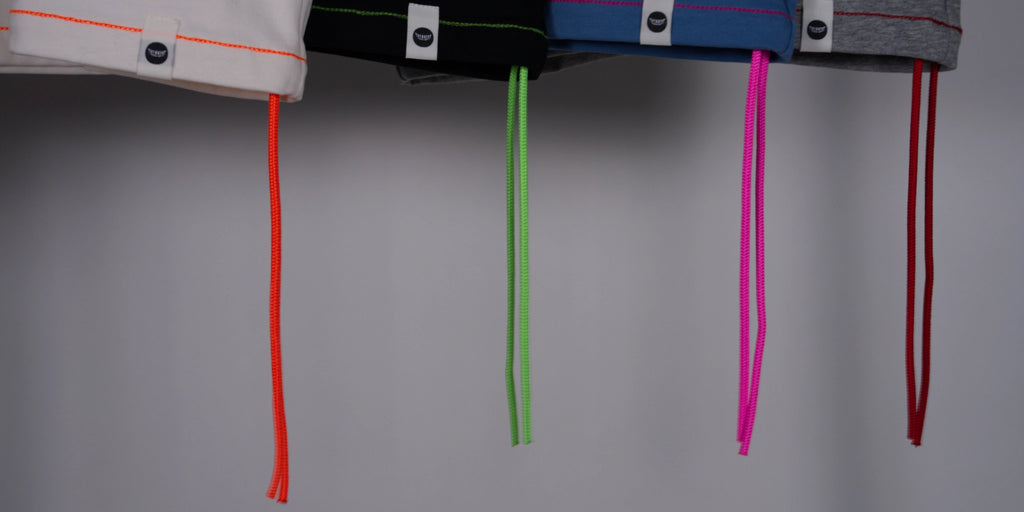 Colorful threads hanging from normal;c t-shirts on a white background.