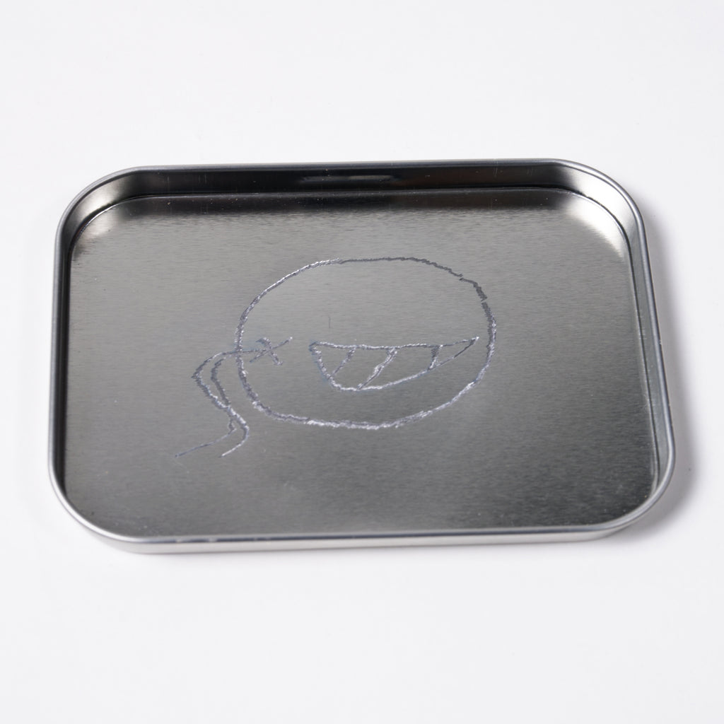 Metal tray with a simple drawing of a face on a white background
