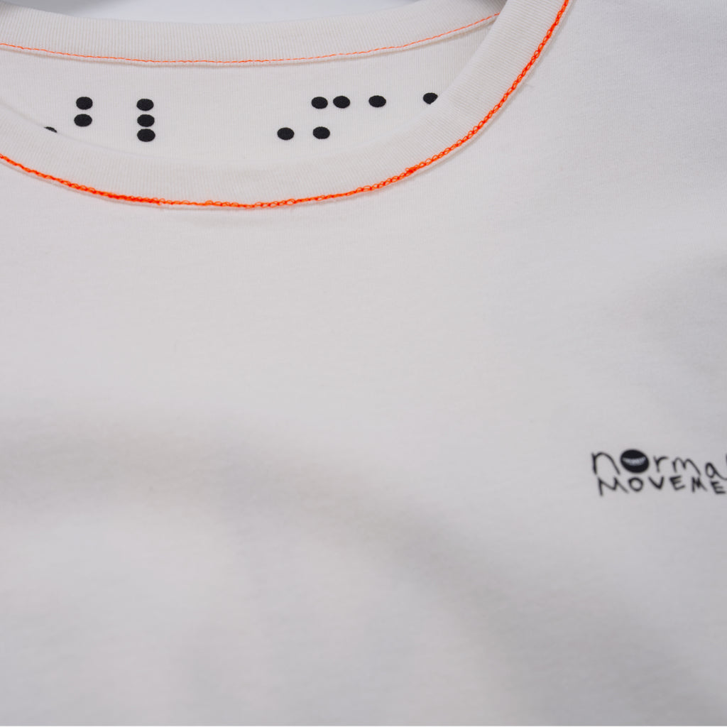 White shirt with orange stitching and normal;c movement logo on a white background