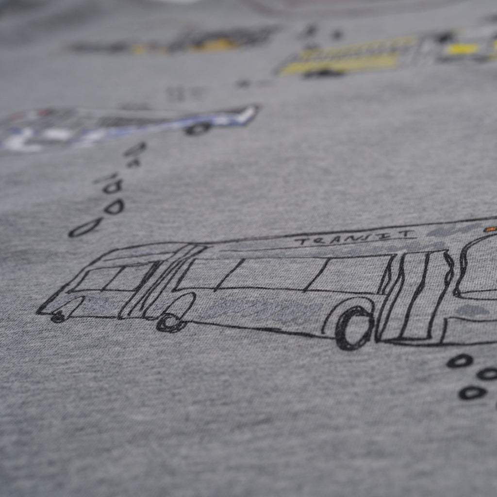 Gray t-shirt with black line drawing of a bus and text on a blurred background