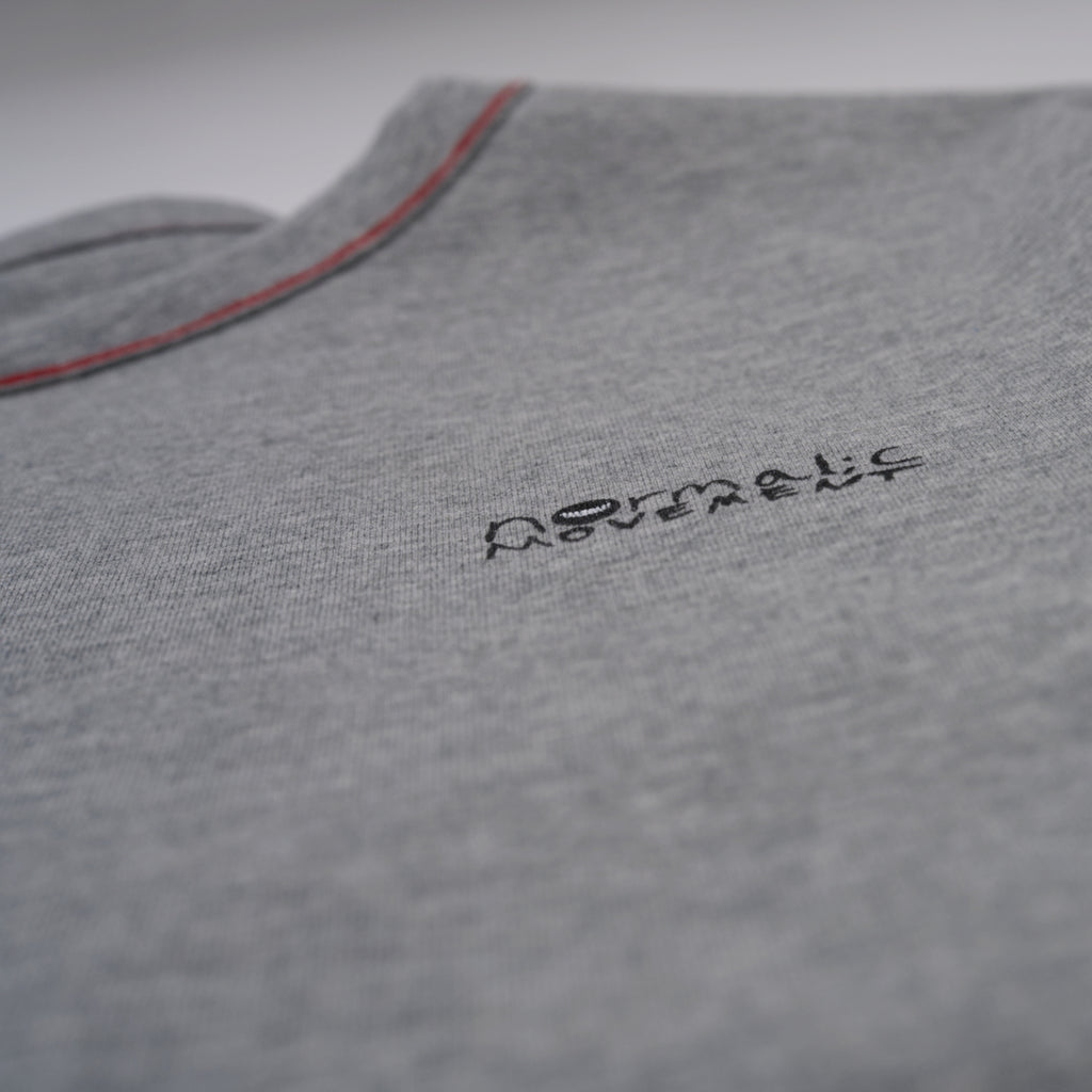 Gray shirt with black normal;c movement logo on a plain background