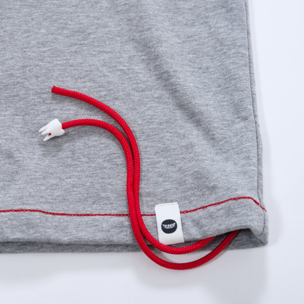 Close up of a gray t-shirt with red threads hanging off of it and white tag on a light gray background